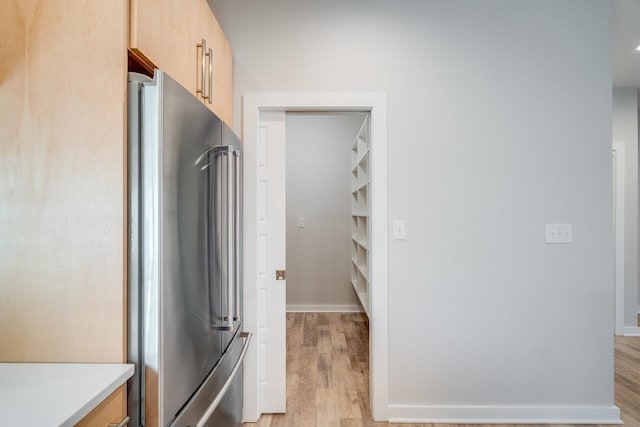 interior space featuring high end fridge, light brown cabinetry, and light hardwood / wood-style flooring