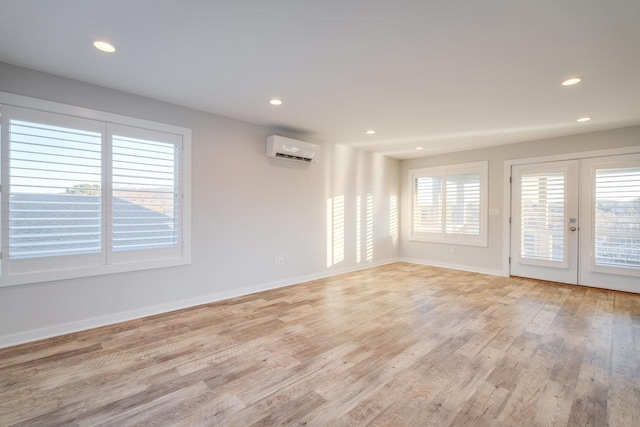 unfurnished room featuring a wall mounted air conditioner, light hardwood / wood-style floors, and french doors