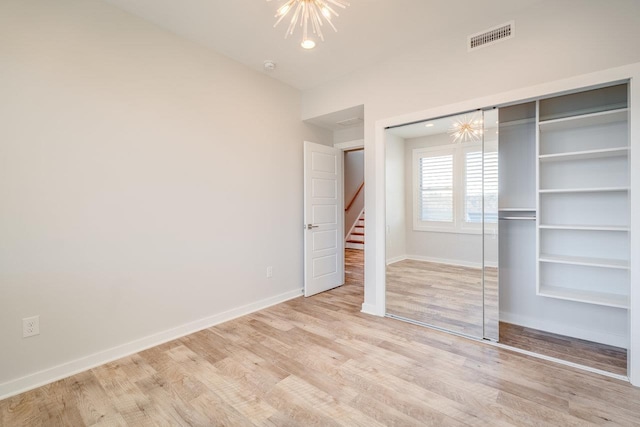 unfurnished bedroom with a closet, an inviting chandelier, and light hardwood / wood-style flooring