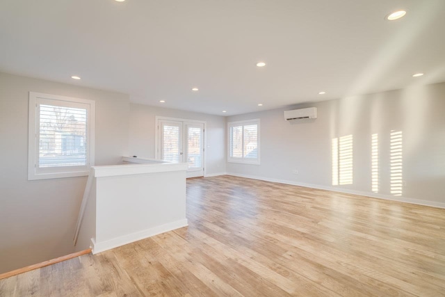 spare room featuring light hardwood / wood-style flooring, an AC wall unit, and french doors