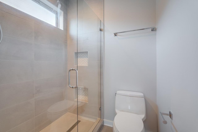 bathroom with toilet and a shower with shower door