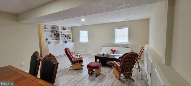 living area featuring light hardwood / wood-style flooring, built in features, and a textured ceiling