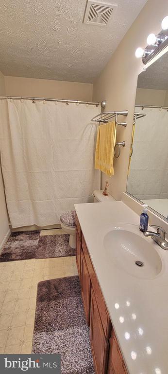 bathroom with vanity, toilet, and a textured ceiling