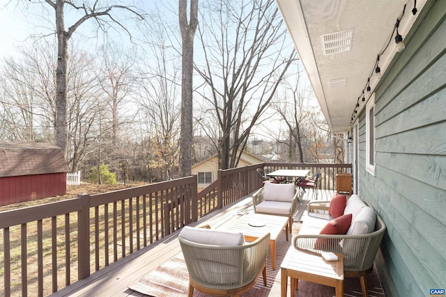 deck with an outbuilding, an outdoor hangout area, and a storage unit