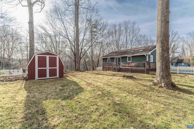 view of yard featuring a deck, a storage unit, an outdoor structure, and fence