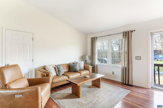 living room featuring baseboards, light wood-style floors, and vaulted ceiling