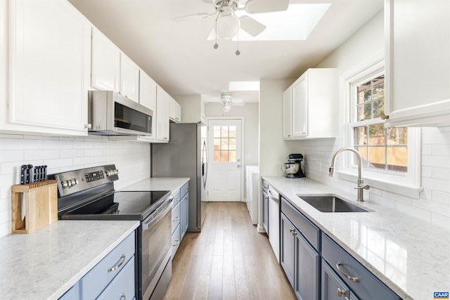 kitchen featuring a sink, a skylight, ceiling fan, and stainless steel appliances