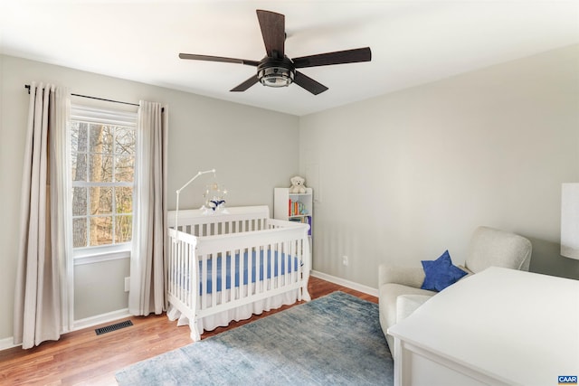 bedroom with visible vents, ceiling fan, baseboards, and wood finished floors