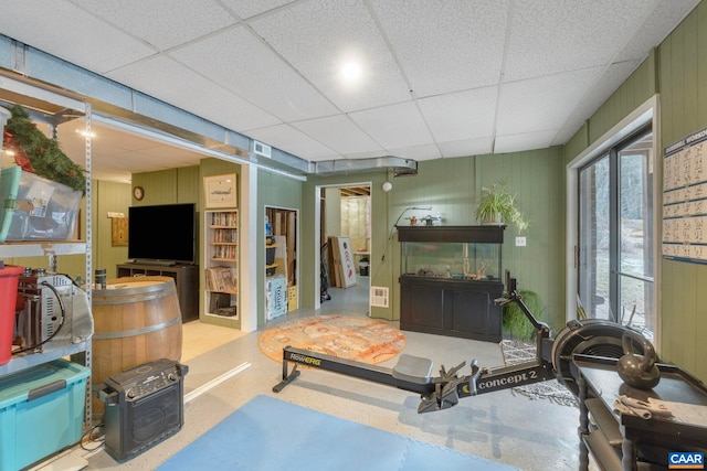 living room featuring a paneled ceiling and wood walls