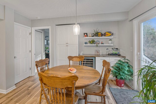 dining room featuring wine cooler, light hardwood / wood-style floors, and bar