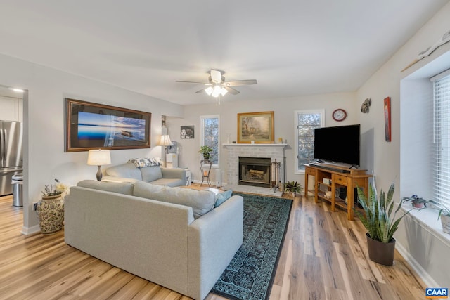 living room featuring hardwood / wood-style floors, a brick fireplace, and ceiling fan