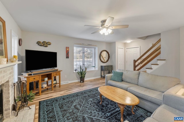 living room featuring a fireplace, wood-type flooring, and ceiling fan