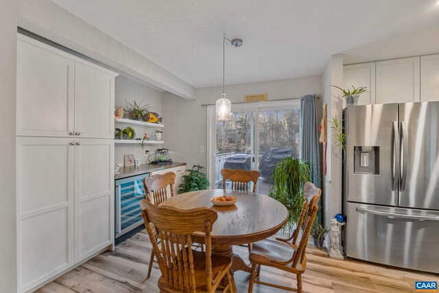 dining space featuring indoor bar, beverage cooler, and light wood-type flooring