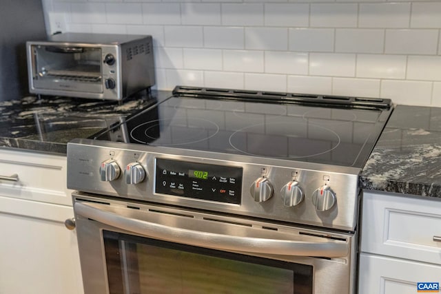 details with backsplash, dark stone countertops, stainless steel electric range, and white cabinets