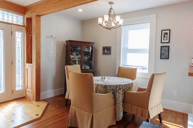 dining space with hardwood / wood-style floors and a notable chandelier