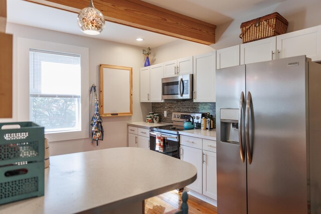 kitchen featuring stainless steel appliances, decorative backsplash, white cabinets, and decorative light fixtures