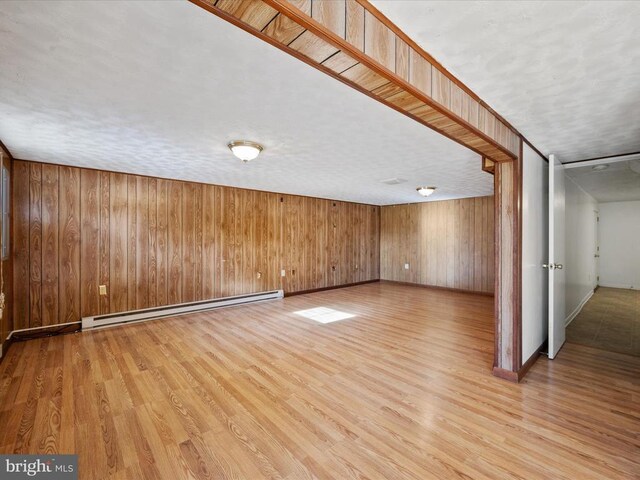 interior space featuring wood walls, light hardwood / wood-style flooring, and a baseboard heating unit