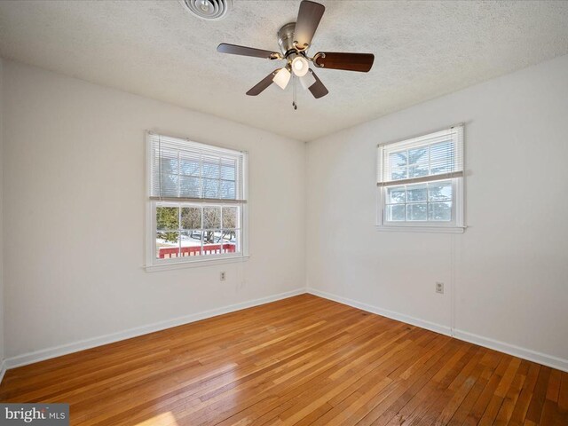 spare room with a wealth of natural light, a textured ceiling, and light wood-type flooring