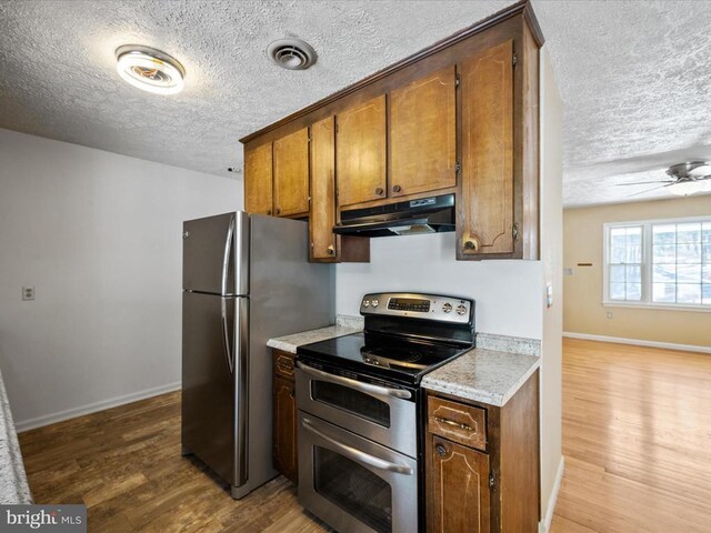 kitchen with appliances with stainless steel finishes, a textured ceiling, ceiling fan, and light hardwood / wood-style flooring