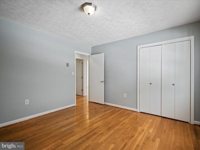 unfurnished bedroom featuring a textured ceiling, light wood-type flooring, and a closet