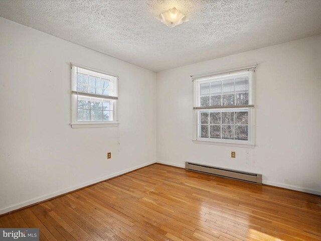 unfurnished room with a baseboard radiator, a textured ceiling, and light wood-type flooring