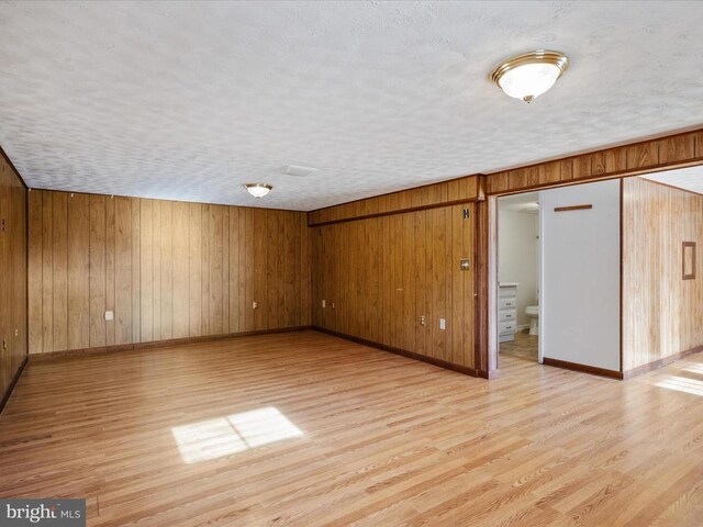 interior space featuring wood walls, light hardwood / wood-style flooring, and a textured ceiling