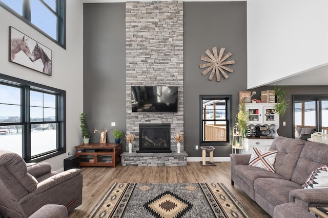 living room featuring a stone fireplace, light hardwood / wood-style flooring, and a towering ceiling