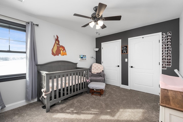 carpeted bedroom featuring a crib and ceiling fan