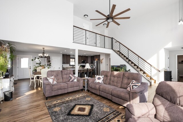 living room with ceiling fan with notable chandelier and dark wood-type flooring