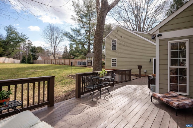 wooden terrace with an outbuilding, a lawn, and fence