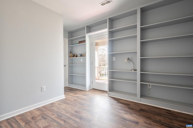 spare room featuring wood finished floors, visible vents, and baseboards