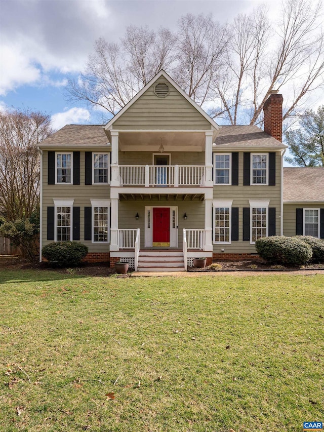 view of front facade featuring a front lawn, a chimney, and a balcony