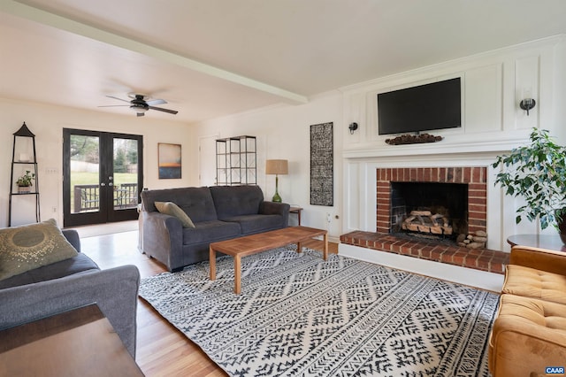 living area with french doors, ornamental molding, a brick fireplace, wood finished floors, and beamed ceiling