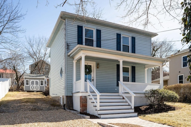 traditional style home featuring a porch, a storage unit, fence, and an outdoor structure