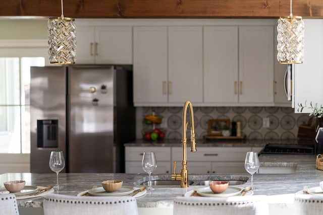 kitchen with a sink, decorative light fixtures, tasteful backsplash, white cabinetry, and stainless steel fridge