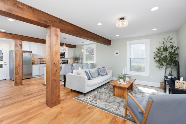 living room featuring beamed ceiling, recessed lighting, baseboards, and light wood-style floors