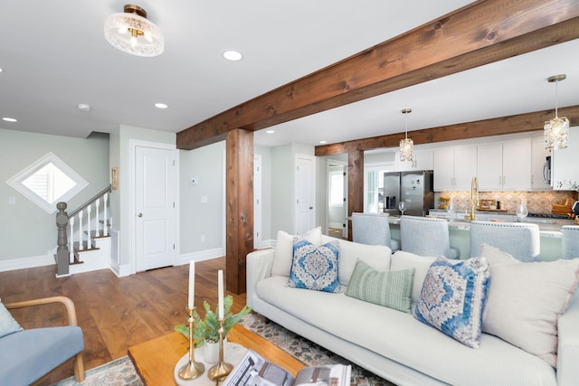 living area with beamed ceiling, wood finished floors, recessed lighting, stairway, and baseboards