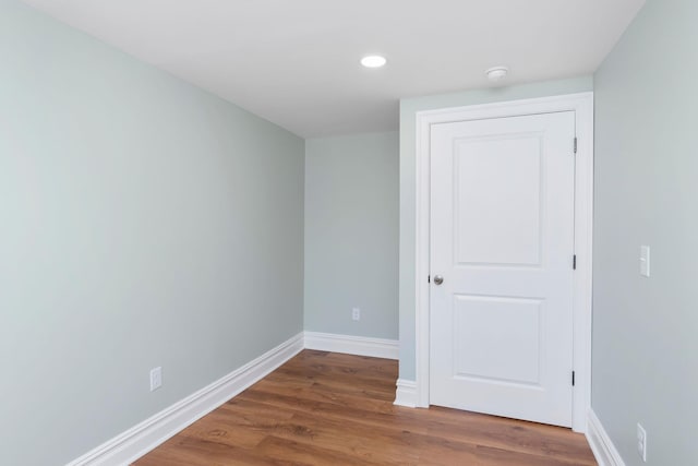 unfurnished room featuring recessed lighting, wood finished floors, and baseboards