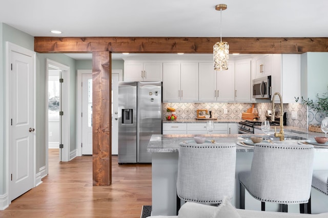 kitchen featuring a kitchen breakfast bar, appliances with stainless steel finishes, white cabinets, and light wood finished floors