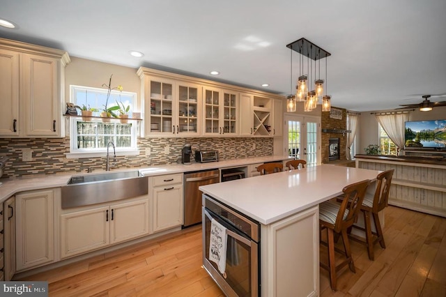 kitchen with a center island, light countertops, cream cabinets, stainless steel dishwasher, and a sink