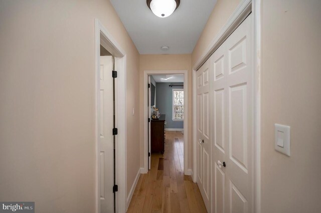 corridor with baseboards and light wood-type flooring