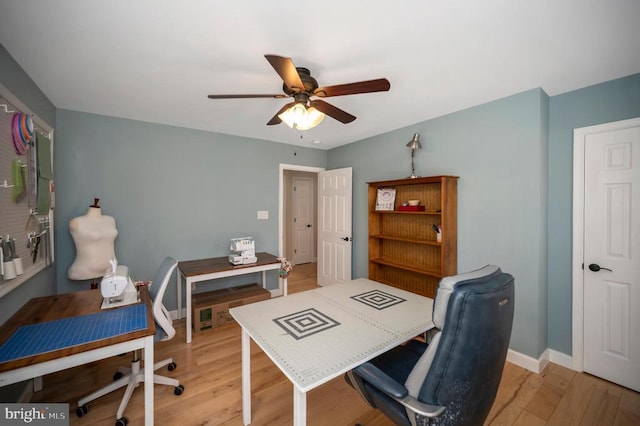 office area with baseboards, light wood-style floors, and ceiling fan