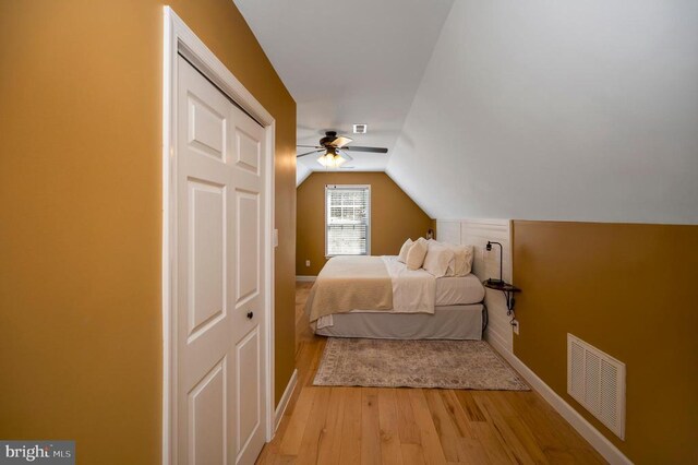 bedroom featuring visible vents, light wood-style flooring, baseboards, lofted ceiling, and ceiling fan