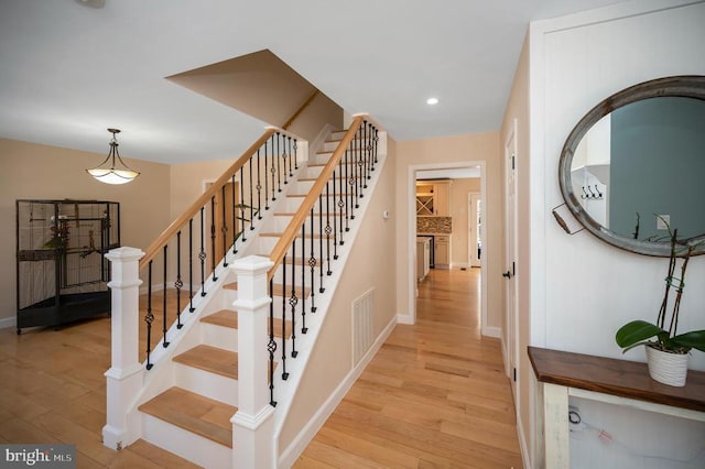 staircase featuring recessed lighting, visible vents, baseboards, and wood finished floors