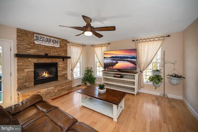 living area with a fireplace, a ceiling fan, baseboards, and hardwood / wood-style flooring