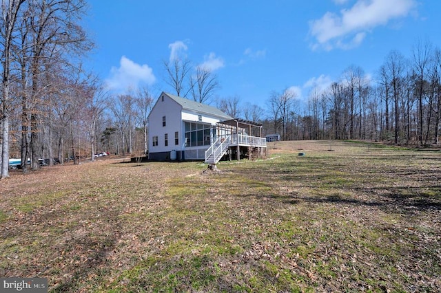 view of property exterior with stairway, a lawn, and a sunroom