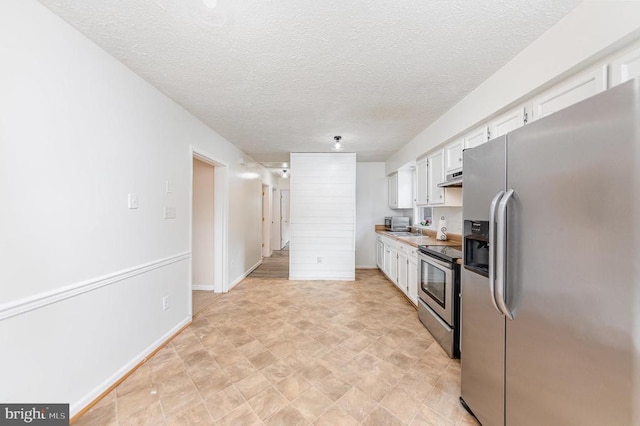 kitchen featuring baseboards, white cabinets, stainless steel appliances, a textured ceiling, and under cabinet range hood