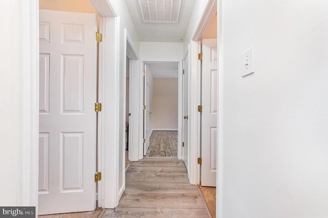 hall with light wood-style floors and visible vents