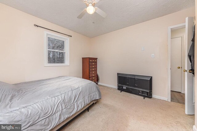 bedroom with a ceiling fan, light carpet, a textured ceiling, and baseboards