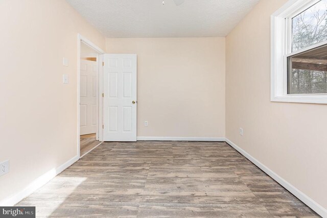 spare room with a textured ceiling, baseboards, and wood finished floors